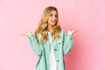 Young caucasian blonde woman confused and doubtful shrugging shoulders to hold a copy space.