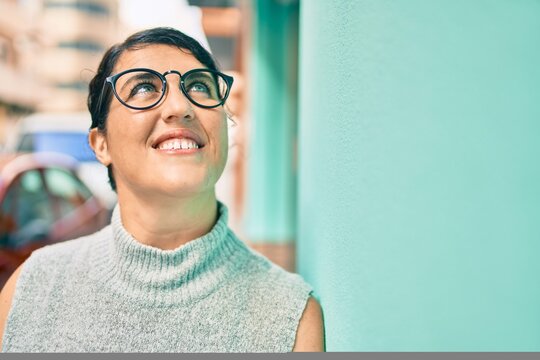 Young plus size woman smiling happy leaning on the wall at the city.