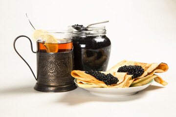 Traditional Russian pancakes with black caviar. In the background is a jar with sturgeon caviar and...