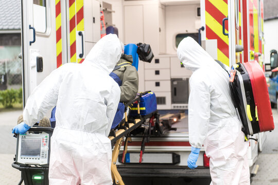 Mitarbeiter des Rettungsdienstes bringen infekti&ouml;sen Patienten in den Rettungswagen