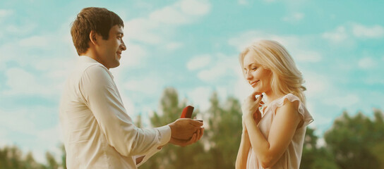 Happy couple, man proposing a ring to his woman outdoors, wedding concept