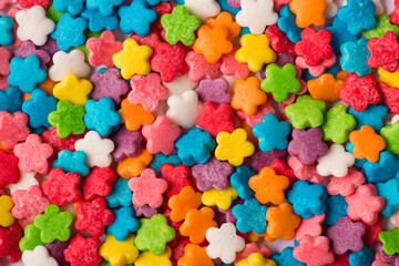 Fototapeta na wymiar Close-up top view photo of small little shiny colorful mini flowers sugar icing textured background