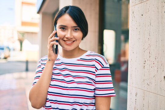 Young latin girl smiling happy talking on the smartphone at the city