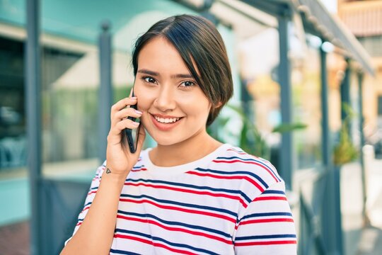 Young latin girl smiling happy talking on the smartphone at the city