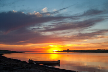 Naklejka na ściany i meble Canoe on the lakeshore at sunset