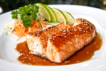 Grilled salmon teriyaki with vegetables and citrus Japanese food on white plate, on black background