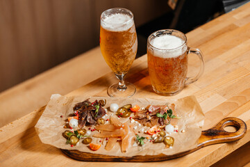 Glasses of beer on the table next to a meat snack. High quality photo