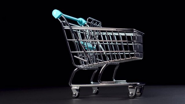 Shiny empty shopping cart closeup in miniature on a black background. Dolly Shot