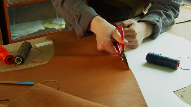 General view of the tanner's desktop, which is preparing to create designer shoes made of genuine leather. Cuts leather with scissors.
