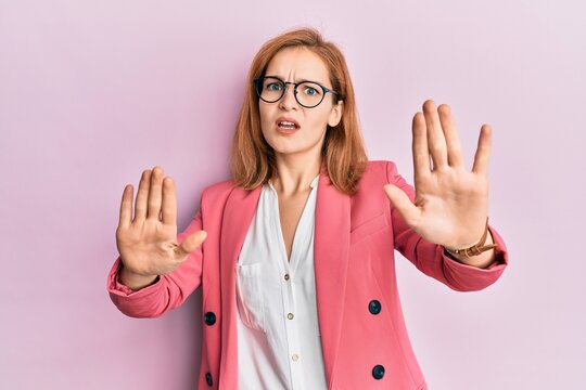 Young caucasian woman wearing business style and glasses doing stop gesture with hands palms, angry and frustration expression