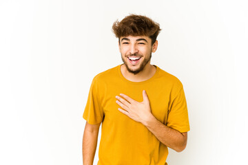 Young arab man on white background laughs out loudly keeping hand on chest.