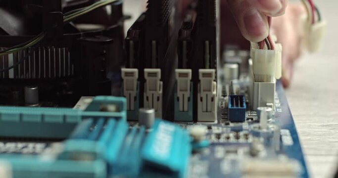 Connecting wires in a computer. Components inside the system unit. Video card and RAM on the motherboard. Connecting a chip in a laptop. Connector with wires. Master technician assembles a computer