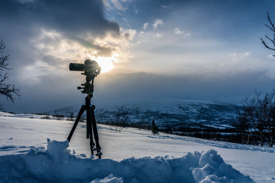 Recording beautiful view of mountain landscape on professional video camera, standing on tripod. Sun, clouds, winter view