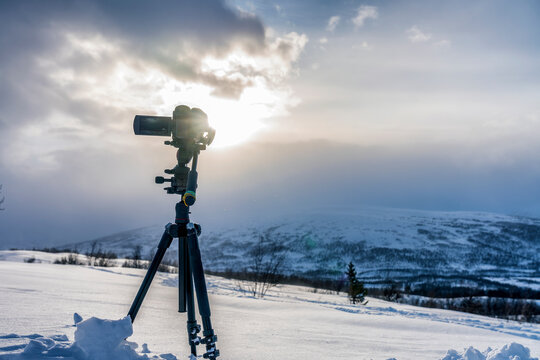 Recording beautiful view of mountain landscape on professional video camera, standing on tripod, close up view. Sun, clouds, winter view