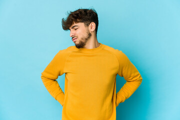 Young arab man on blue background suffering a back pain.