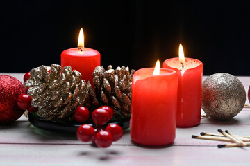 Lighted red candles surrounded by holiday decorations.