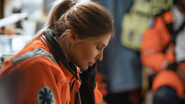 Calm and Happy Female EMS Professional Paramedic Mentally Prepares in Ambulance Vehicle on the Way to a Call. Emergency Medical Technicians are on Their Way to a Call Outside the Healthcare Hospital.