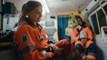 Calm and Happy Female EMS Professional Paramedic Mentally Prepares in Ambulance Vehicle on the Way...