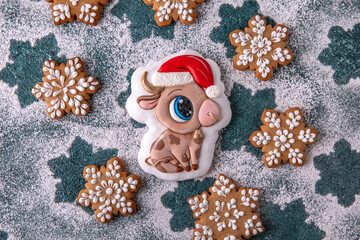Christmas homemade Gingerbread glazed and painted in the shape of a bull and snowflakes, symbol of the year 2021. Blue background. Holiday sweets for decoration and gifts.