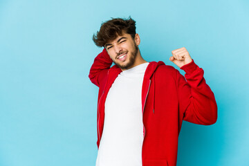 Young arab man on blue background stretching arms, relaxed position.