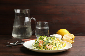 Delicious zucchini pasta with arugula and shrimps served on wooden table. Space for text