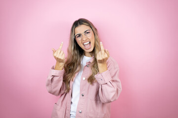 Young beautiful blonde woman with long hair standing over pink background showing middle finger...