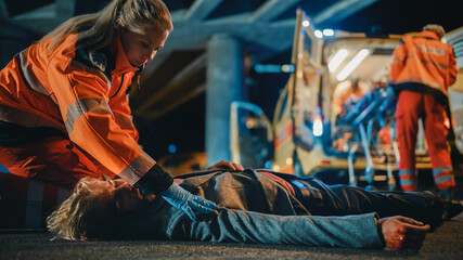 Team of EMS Paramedics Quickly Jump Out from Ambulance Vehicle. Female Doctor Starts First Aid. Emergency Care Assistants Arrived on the Scene of a Traffic Accident on a Street at Night. © Gorodenkoff