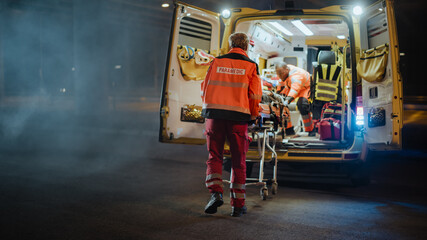 Team of EMS Paramedics React Quick to Provide Medical Help to Injured Patient and Get Him in Ambulance on a Stretcher. Emergency Care Assistants Arrived on the Scene of a Traffic Accident on a Street. © Gorodenkoff