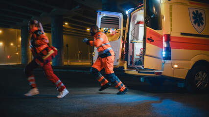 Team of EMS Paramedics Quickly Jump Out from Ambulance Vehicle. Female Doctor Brings First Aid Kit. Emergency Care Assistants Arrived on the Scene of a Traffic Accident on a Street at Night. © Gorodenkoff