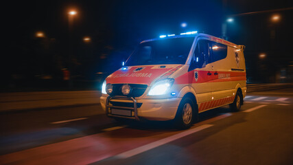 Fototapeta na wymiar Parallel Shot of a Moving Ambulance Vehicle with Working Strobe Light and Signal Driving to Emergency Call on a City Urban Street at Night. Emergency Paramedics Rescue Van with Medical Cross Logo.