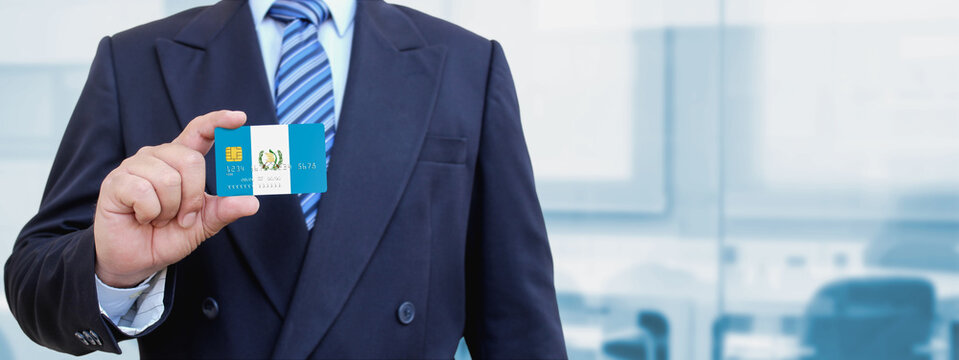 Cropped image of businessman holding plastic credit card with printed flag of Guatemala. Background blurred.