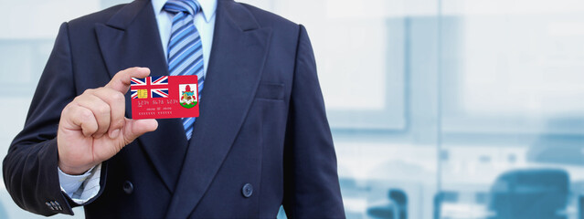 Cropped image of businessman holding plastic credit card with printed flag of Bermuda. Background...