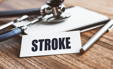 The word STROKE is written on a card on a wooden table with medical background. Medicine concept.