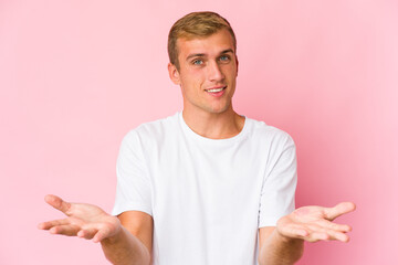 Young caucasian handsome man makes scale with arms, feels happy and confident.