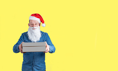 Fototapeta na wymiar courier in a blue denim shirt and santa claus hat with boxes in his hands on a yellow background
