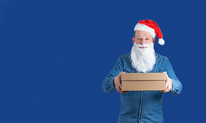 courier in a blue denim shirt and santa claus hat with boxes in his hands on a blue background