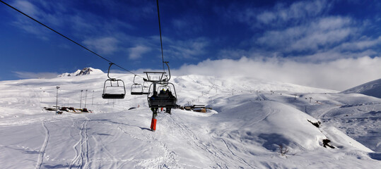 Fototapeta na wymiar Chair-lift and off-piste slope in sun day