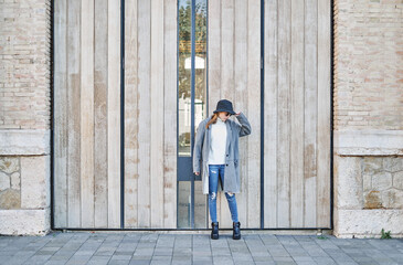 Portrait young pretty Caucasian girl with sunglasses, dressed in a gray jacket and a white sweater and a hat.