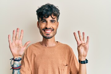 Young hispanic man wearing casual clothes showing and pointing up with fingers number nine while...