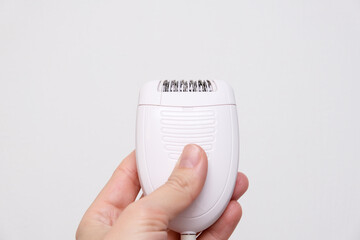 Unwanted extra hair removal, woman holding an electric epilator against white background, home...