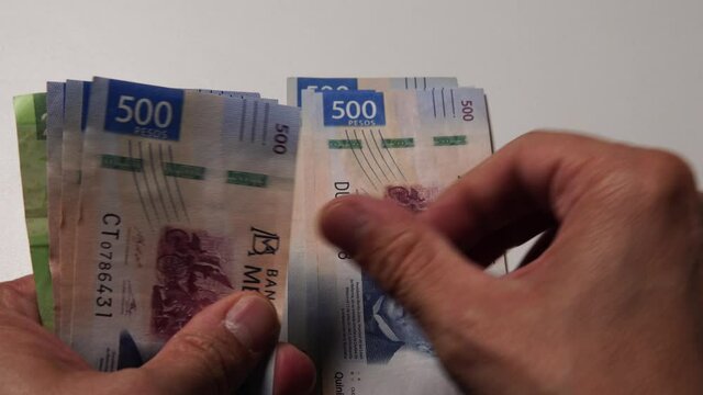 Unas manos cuentan billetes de 500 pesos mexicanos frente a la c&aacute;mara