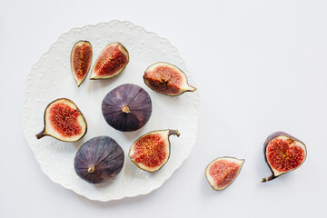 Fresh sliced and whole ripe figs In Plate on white background. Food photo background. Flat lay, Top view. Copy space.