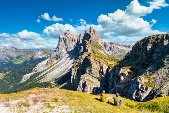 Two men looking at Seceda peaks. Trentino Alto Adige, Dolomites Alps, South Tyrol, Italy. Odle mountain range, Val Gardena. Majestic Furchetta peak