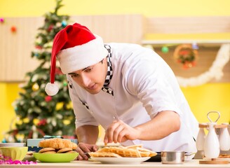 Young chef husband working in kitchen at Christmas eve