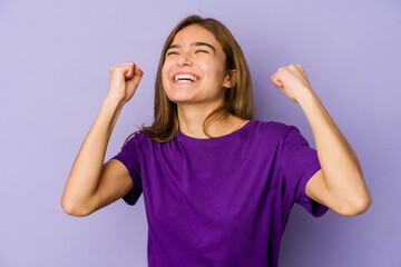 Young skinny caucasian girl teenager on purple background celebrating a victory, passion and enthusiasm, happy expression.