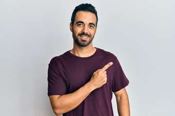 Young hispanic man wearing casual clothes smiling cheerful pointing with hand and finger up to the side