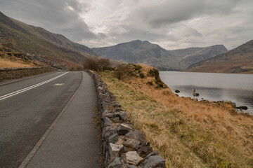 Shores of Llyn Ogwen (lake Ogwen), alongside the A5 road in Snowdonia, Wales, UK. Glyderau mountain range in the distance at the far end of the lake. Winter scene, taken in January.