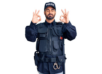 Young hispanic man wearing police uniform relaxed and smiling with eyes closed doing meditation gesture with fingers. yoga concept.