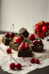 Brownie cake pieces. Homemade tasty chocolate brownie pieces with chocolate and fresh berries. Side view. Vertical orientation