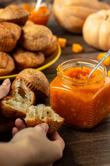 Pumpkin jam. Tasty homemade sweet spicy vegetable jam in a glass jar. Profiteroles and pumpkins background. Vertical orientation
